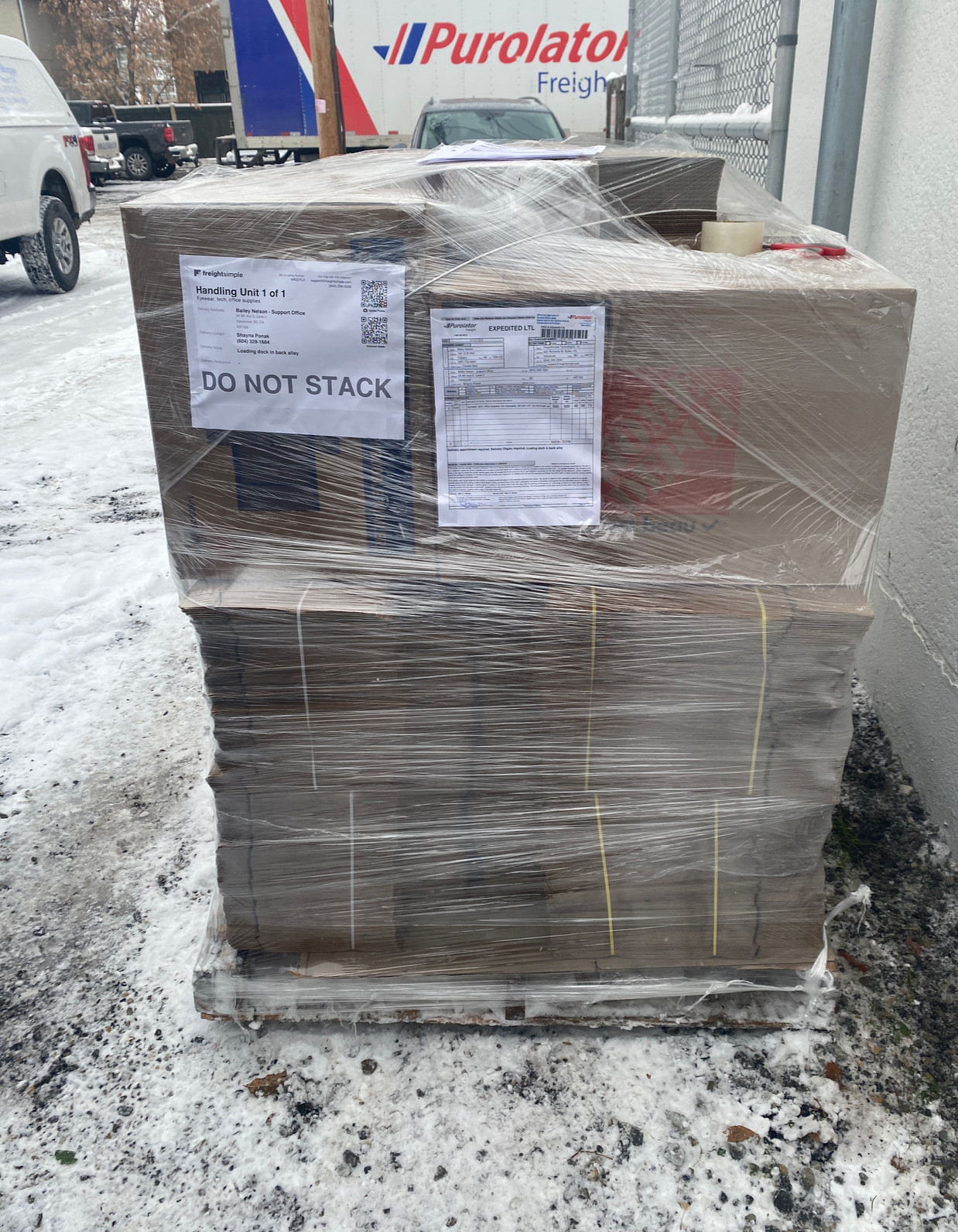 Wrapped pallet with FreightSimple shipping labels at pickup dock